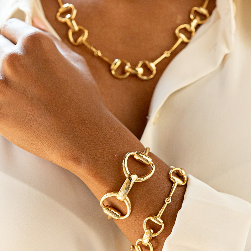 Gold bracelet and necklace on a person wearing a white shirt