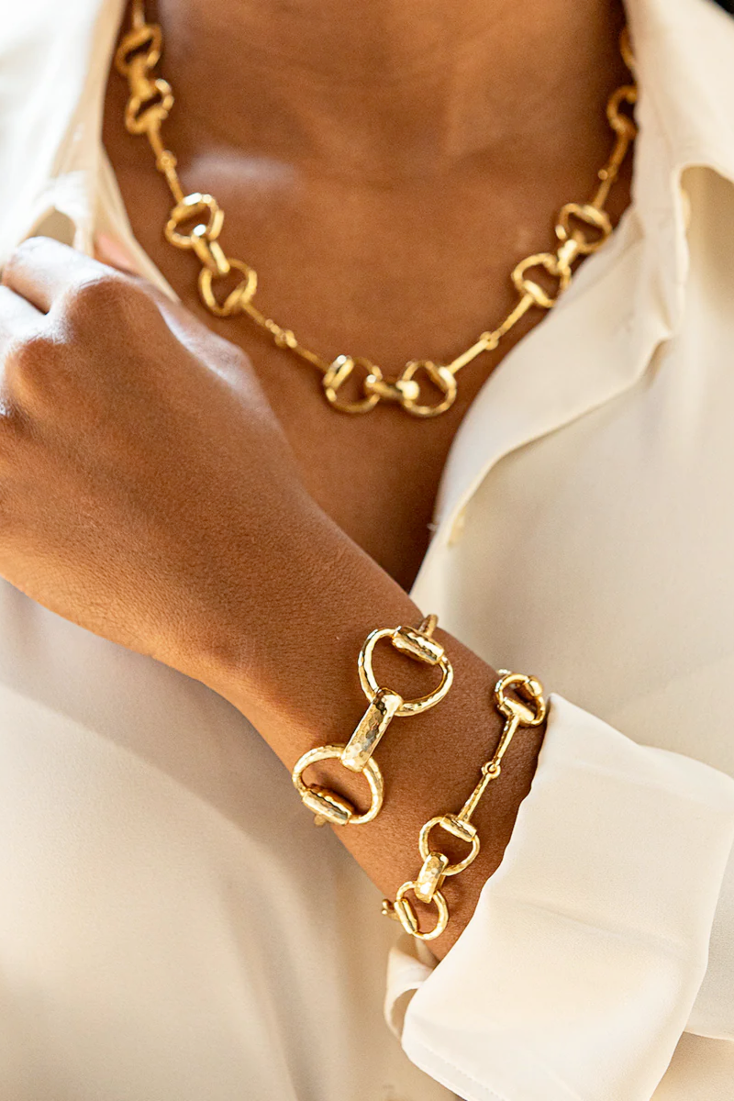 Gold bracelet and necklace on a person wearing a white shirt