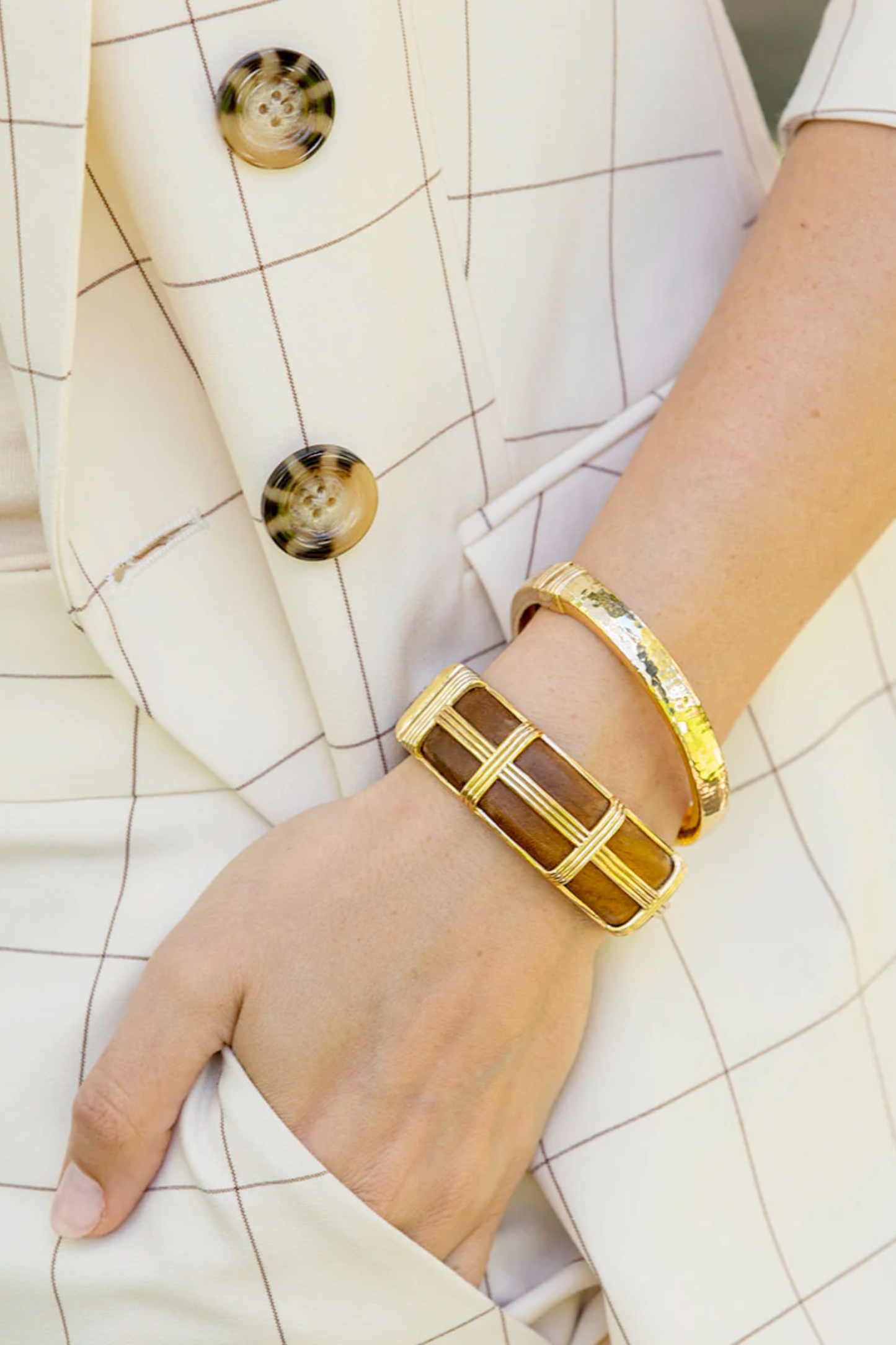 Gold bracelet on a wrist with a white textured background
