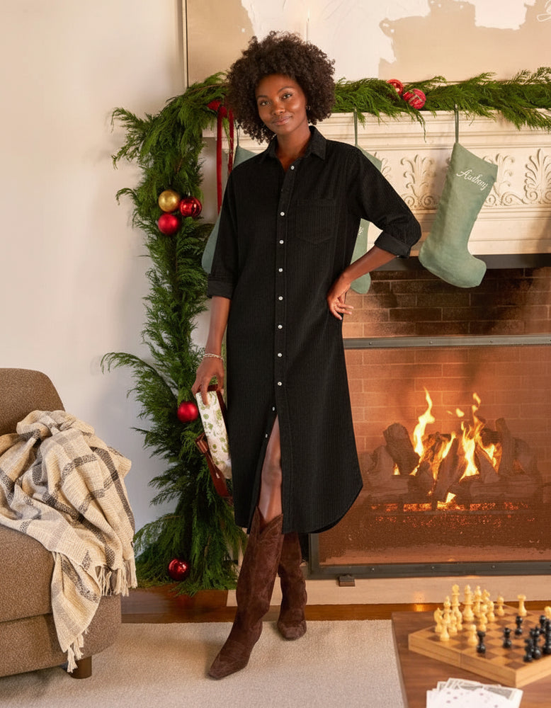 
                  
                    Woman standing in black corduroy dress with holiday decorations.
                  
                