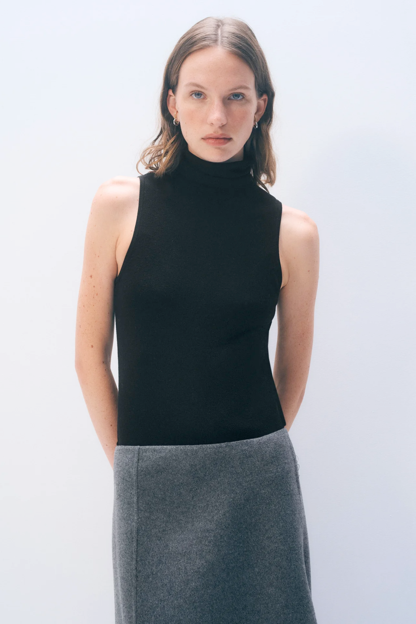 Model wearing a sleeveless black turtleneck from White & Warren