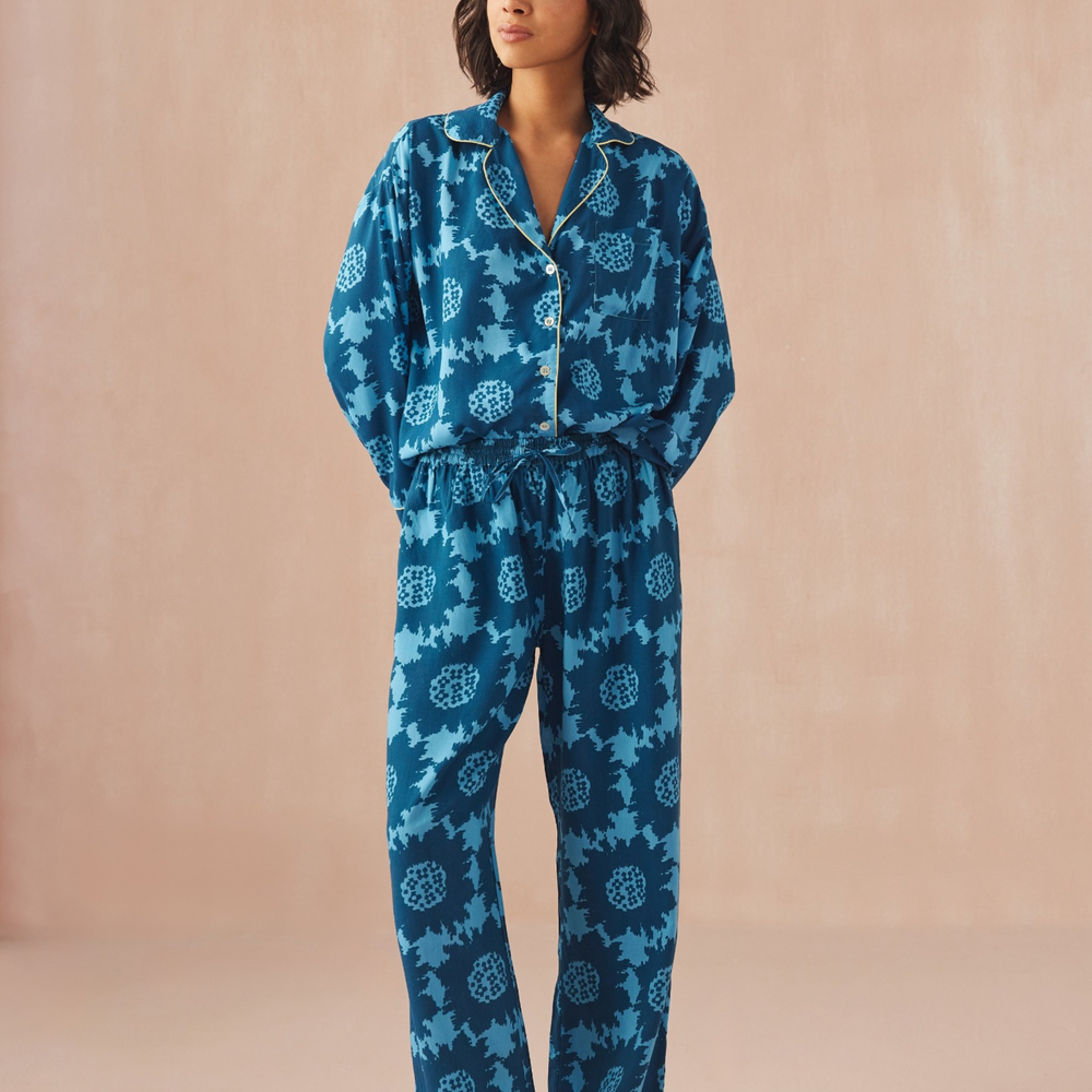 Woman wearing patterned pajamas from Omika standing against a beige background